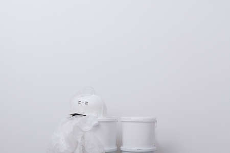 buckets of paint, protective clothing and a hard hat against a white wall, there is a place for writingの写真素材