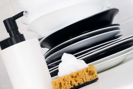 there is clean dishes on the table next to the detergent and a sponge, close-up