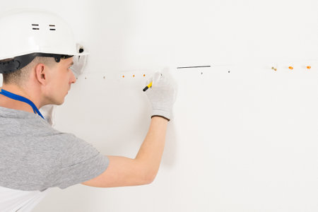 a worker draws a straight line on a white wall, side viewの写真素材