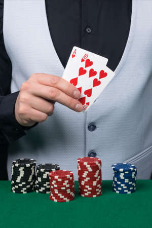 a croupier in a white vest holds victory cards in the game
