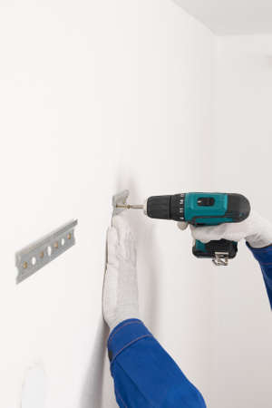 the worker's hands fasten the iron plates to the wall with a screwdriverの写真素材