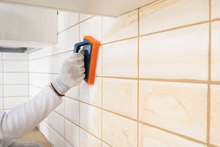 a ceramic tile laying master wipes the seams with a special spongeの写真素材