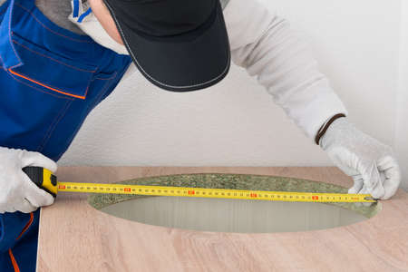 a worker checks the hole for installing a sink in the countertop of kitchen furnitureの写真素材