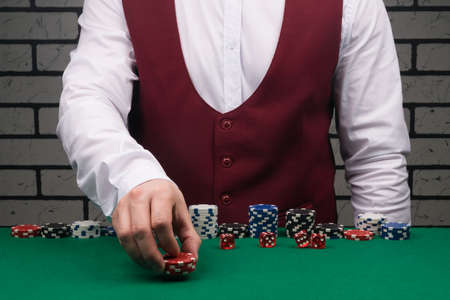 the croupier at the green poker table bets with red chipsの写真素材