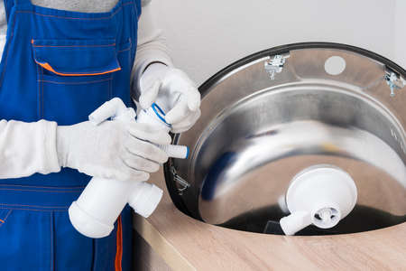 The kitchen assembler installs a siphon on the sinkの写真素材