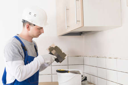 worker applies adhesive to wall tiles, side viewの写真素材
