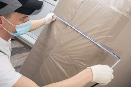 a delivery man measures a large box, close-upの写真素材