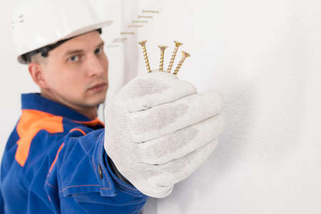 a kitchen furniture fitter holds self-tapping screws in his hand, close-up viewの写真素材