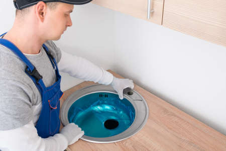 the kitchen assembler installs the sink in the countertopの写真素材