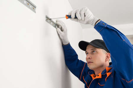 the master attaches the iron plates to the wall with a screwdriverの写真素材