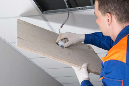 close-up of the installation of a lamp in a suspended ceiling, by an electrician professionalの写真素材