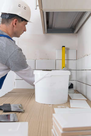 the tile installation wizard measures the correct laying of white tiles, using the yellow levelの写真素材