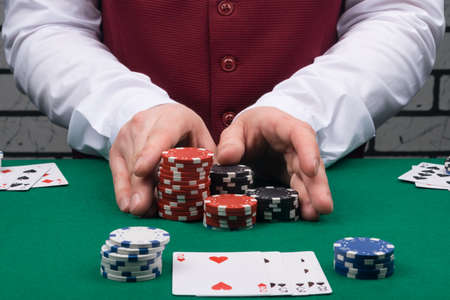 the croupier in the casino, at the green table, gives a big win with chips to the player with the cards oppositeの写真素材
