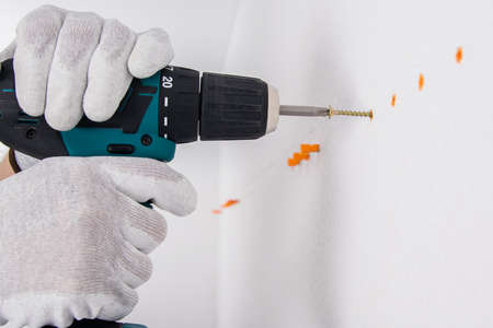 a screwdriver twists a self-tapping screw into a cork in a concrete wall close-upの写真素材