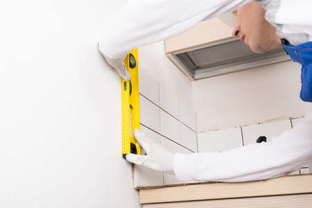 checking the flatness of the laid ceramic tiles on the wall in the kitchenの写真素材