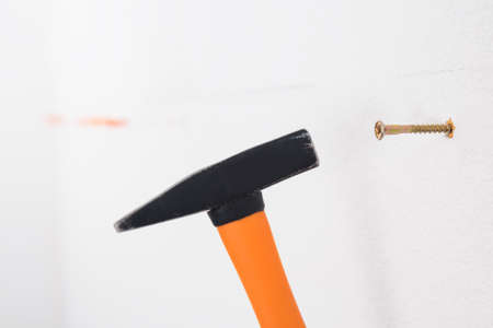a hammer drives a dowel into a white concrete wall, close-upの写真素材