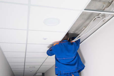 the master adjusts the electrical equipment above the false ceilingの写真素材