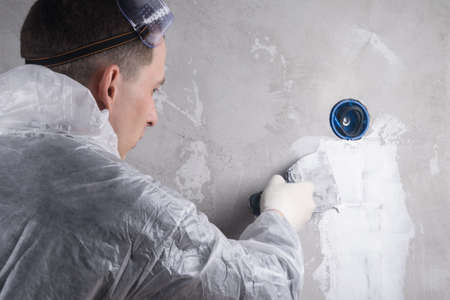 the plasterer seals the wall after the installation of the electrical wiringの写真素材