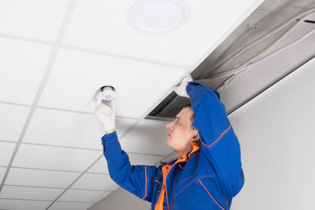 a worker adjusts the luminaire in the false ceilingの写真素材