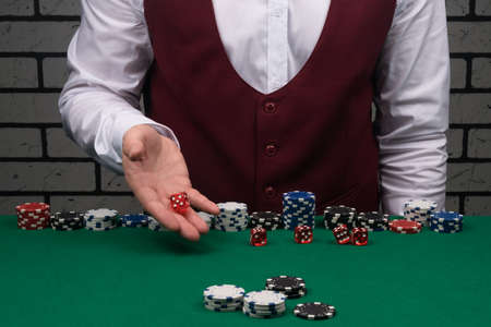 the dealer's hands throw red dice on the green cloth of the poker tableの写真素材