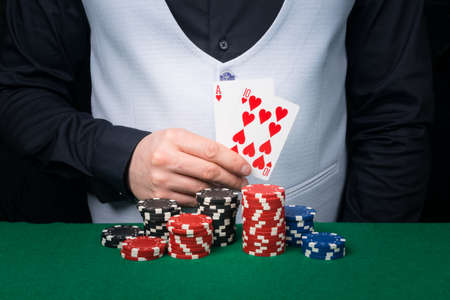 close-up of two red cards in the hands of the croupier, showing the players at the green tableの写真素材