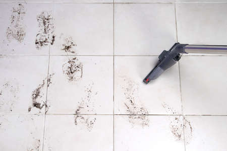 on the white tile floor, a washing vacuum cleaner removes dirty shoe marks after the street, there is a place for the inscriptionの写真素材