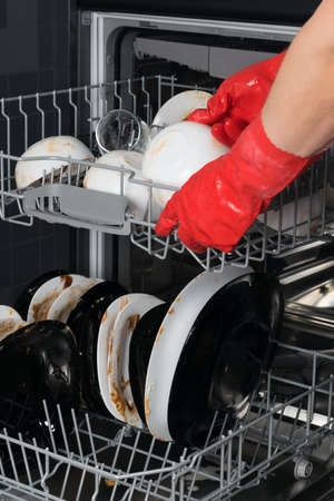 hands in protective gloves, clean plates of large food debris, for putting in the dishwasherの写真素材