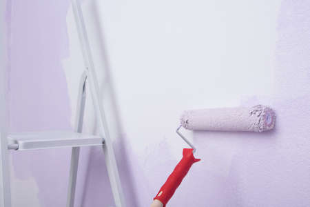 renovation, roller with handle and folding ladder, on the background of the wall, paint application, close-upの写真素材