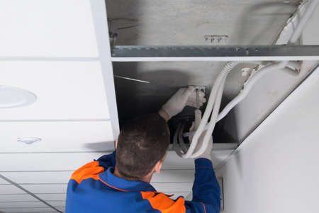 the master opened the suspended ceiling and installs the hidden wiring, fixing it after repairの写真素材