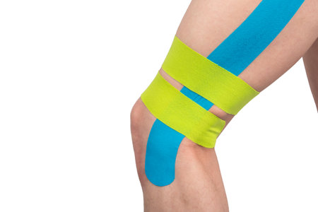 on a white background, knee with Kinesio tapes pasted on to relieve stress and protect against damage when playing sportsの写真素材