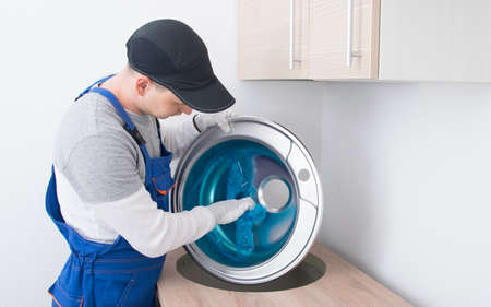 a furniture collector in a protective uniform, removes the protective film from the metal sink to insert it into a cut-out hole in the countertop of the kitchen furnitureの写真素材