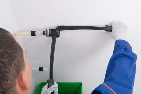the plumber expands the plastic pipe with a press to install the threadの写真素材