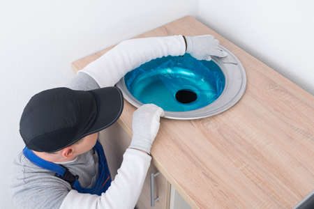 a furniture collector in a protective uniform inserts a metal sink into a cut-out hole in the countertop of kitchen furnitureの写真素材