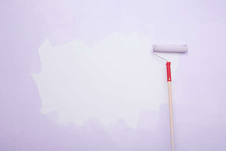 roller with a handle, on the background of the wall, applying paint, there is a place for the inscriptionの写真素材