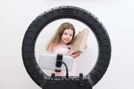 a girl blogger, in the center of a circular lamp and a smartphone, makes a review of the package for unpackingの写真素材