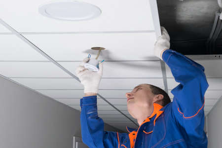 close-up of the installation of a motion sensor for lighting automation, for workers in professional uniformsの写真素材