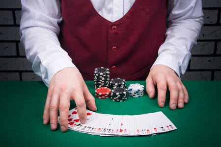close-up of an open deck of cards arranged in a semicircle on the table, with the hands of a croupierの写真素材