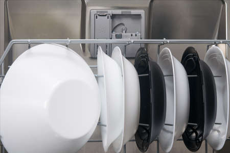 against the background of the door of the dishwasher and the container for cleaning agent, a grid with plates is extendedの写真素材