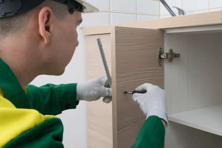 master kitchen furniture assembler, installs the handle on the kitchen cabinet doorの写真素材