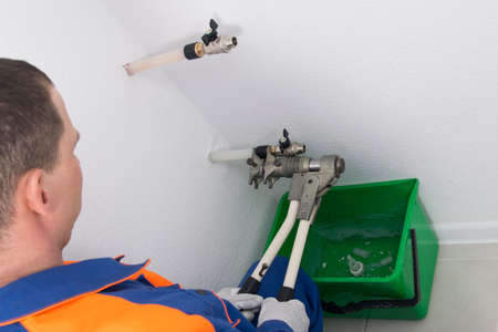the process of installing a threaded copper coupling, using a machine tool, in the hands of a workerの写真素材