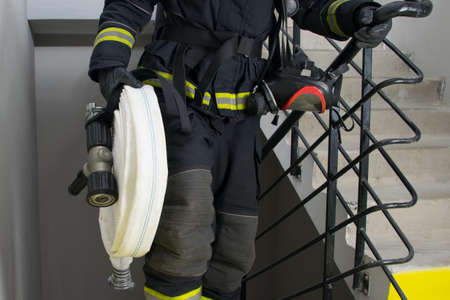 close-up of a firefighter holding water handling equipment, barrel and sleevesの写真素材