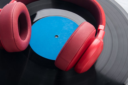 red studio headphones lying on the background of retro vinyl records, close-upの写真素材