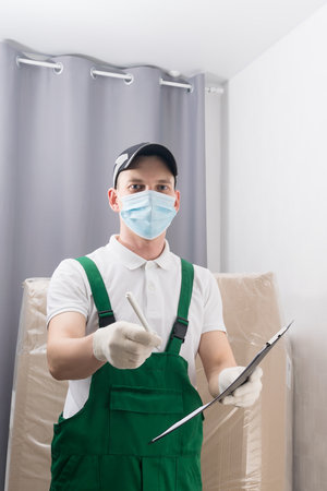 a masked courier delivered the goods to the buyer and asks to sign a documentの写真素材