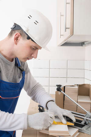 the master makes markings on ceramic white tiles for cutting, finishing workの写真素材