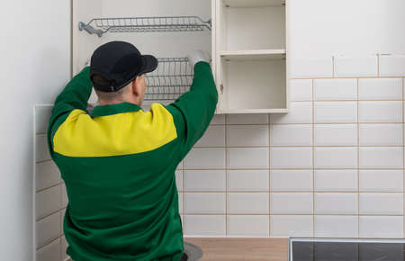 Kitchen furniture assembler assembles upper cabinets, rear viewの写真素材