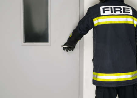 a man in a fireman's uniform opens the door, rear viewの写真素材