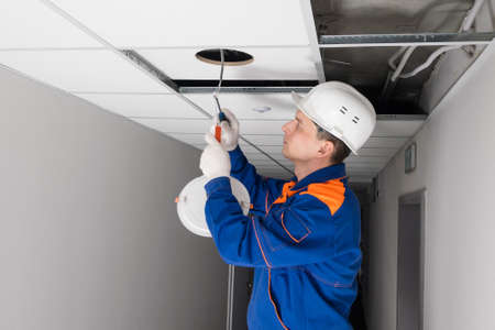 an electrician installing lighting in a false ceiling, side viewの写真素材