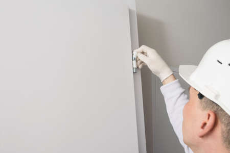 door installation worker installs plastic protection on the hingesの写真素材