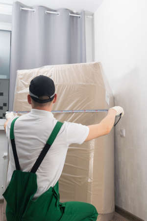 the deliveryman measures the dimensions of a large cardboard box with goodsの写真素材