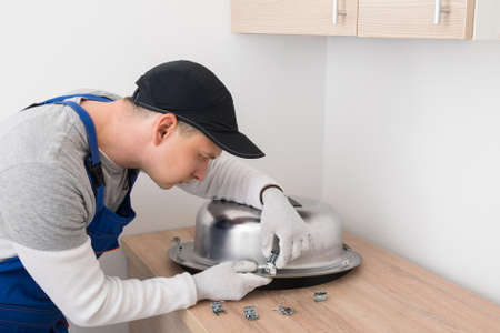 kitchen furniture assembly worker inserts fixtures into the sink to secure itの写真素材